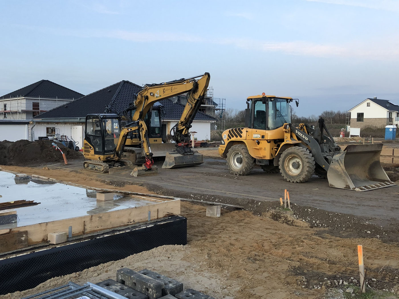 Bagger und Radlader von Berkhan Erdbau im Abendlicht auf einer Neubau-Baustelle